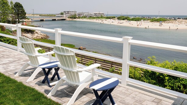 A waterfront patio with Adirondack chairs and a view of a beach and ocean. - Terrace by the Sea (Ogunquit)