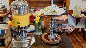 A buffet setup with a juice dispenser, a variety of food items, and a decorative vase with flowers. - Terrace by the Sea (Ogunquit)