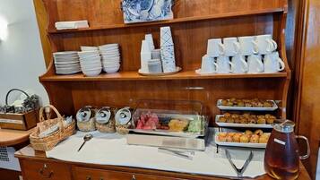 A buffet setup with various food items, plates, cups, and a pitcher of iced tea.
