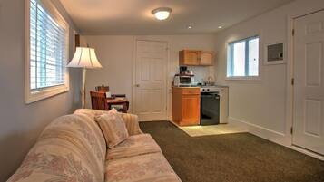 A compact living space with a sofa, a dining table, a kitchenette, and a small window.