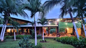 A resort with outdoor seating, palm trees, and a well-maintained lawn. - Angels Ecolodge (Veintisiete de Abril)