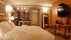 Una habitación de hotel con cama, televisor, una mesita con un florero y una silla.