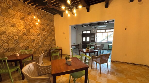 A dining area with wooden tables and chairs, patterned walls, and hanging light bulbs. - Nicte Ha Campeche (Campeche)