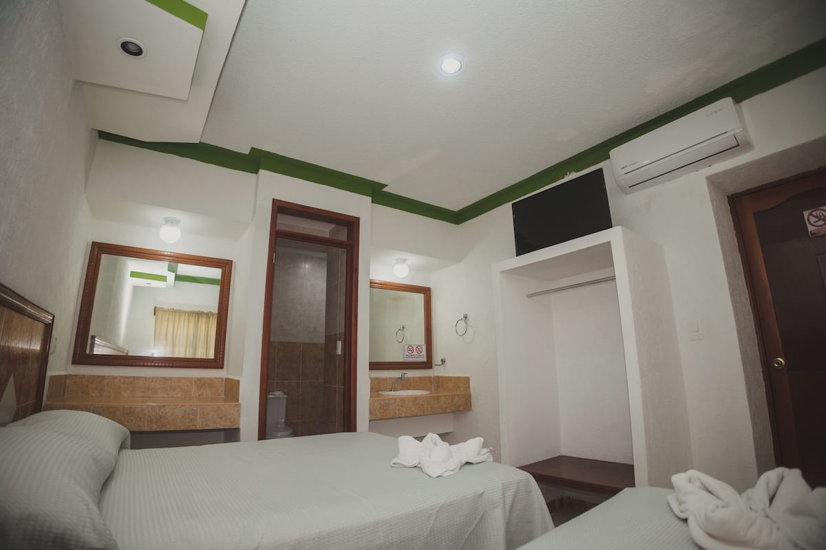 A hotel room with two beds, a bathroom, and a wardrobe.