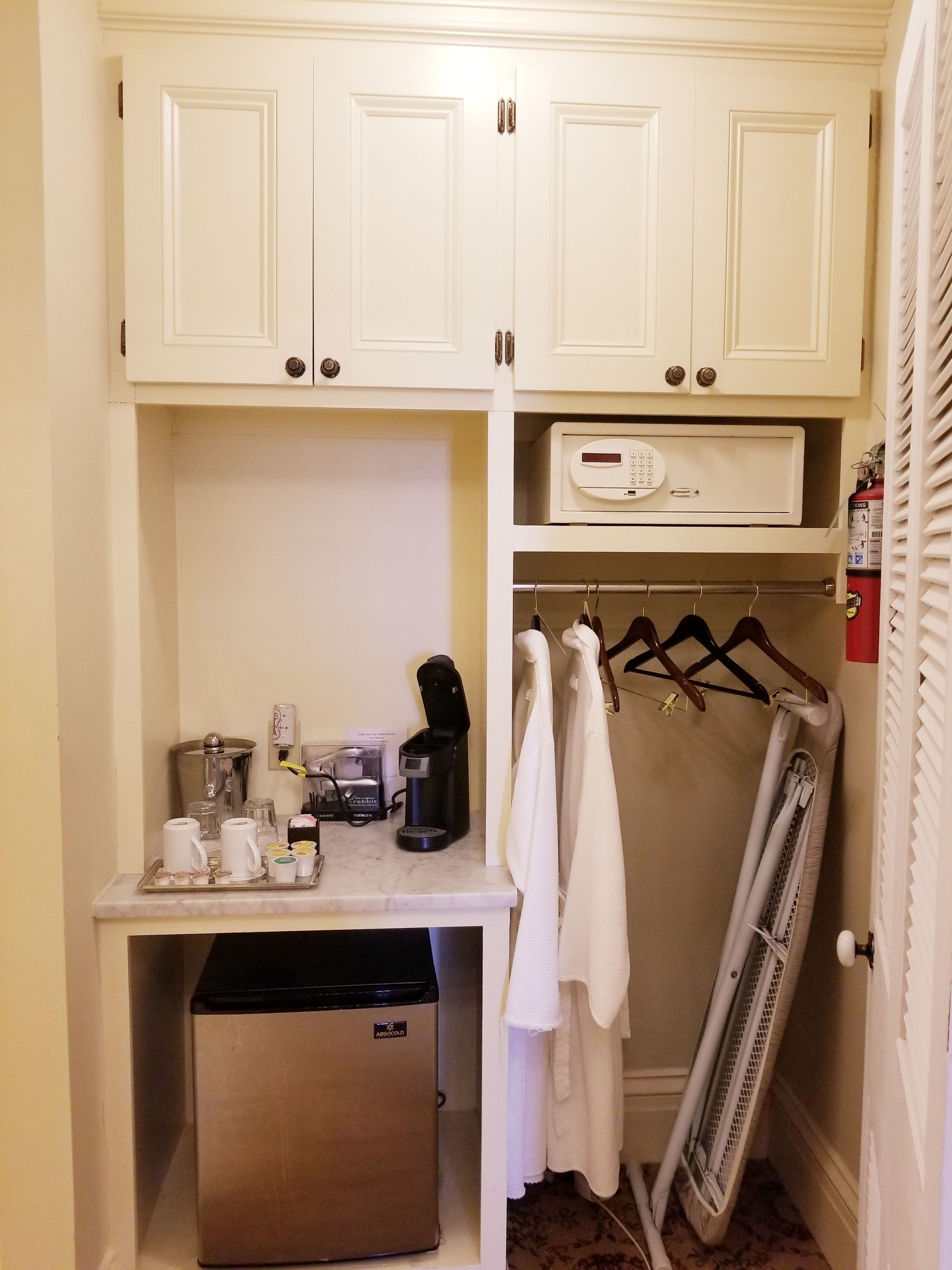 Una kitchenette compacta con cafetera, lavavajillas y un tendedero.