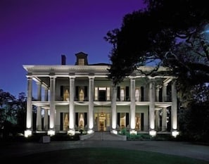 A large, symmetrical building with a central entrance flanked by columns, surrounded by a well-maintained lawn.