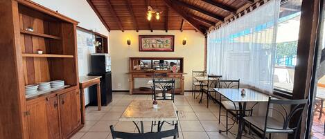 A cozy kitchen with wooden cabinets, a refrigerator, and a dining area with tables and chairs.