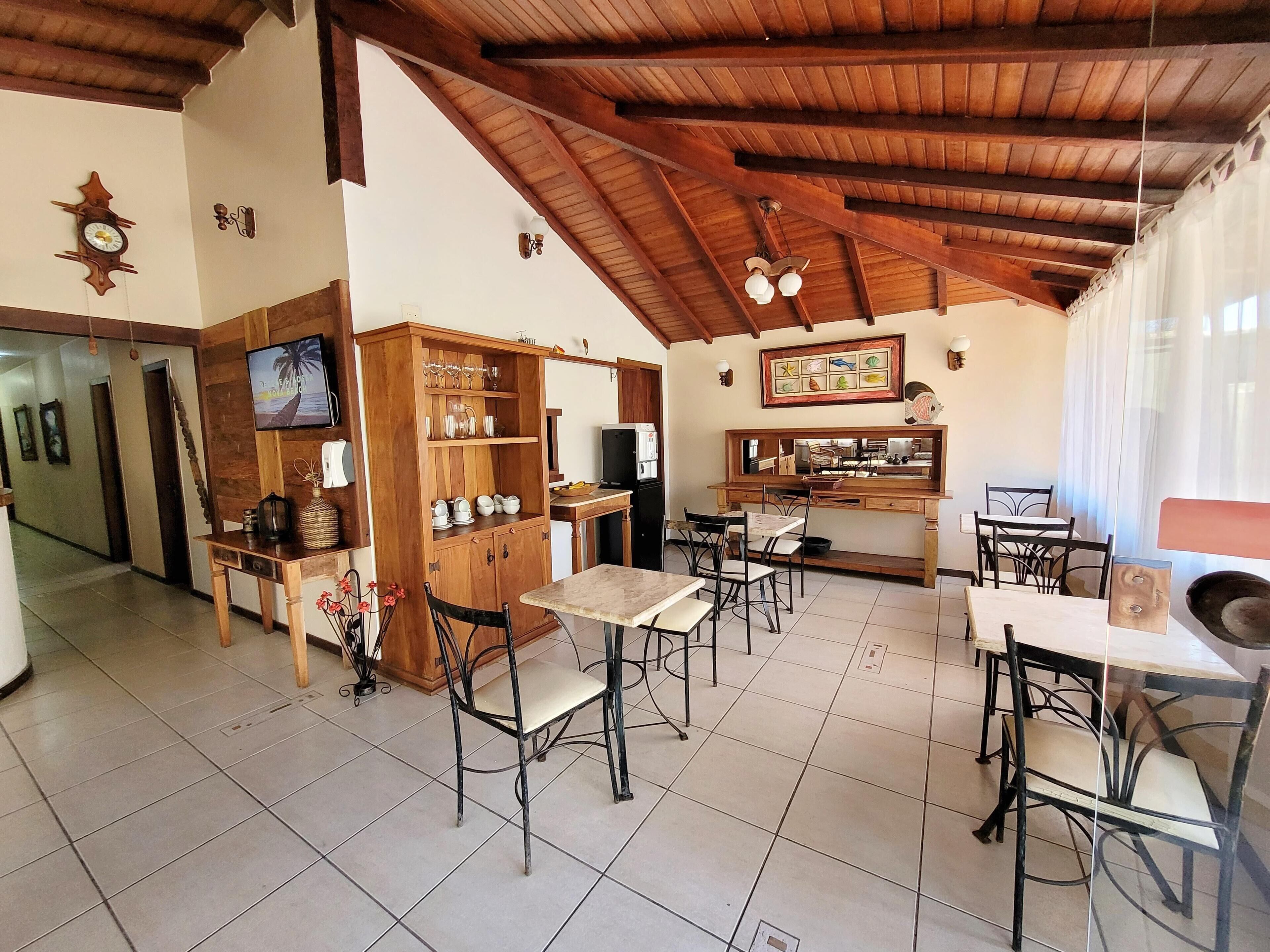 A cozy restaurant with wooden furniture, a tiled floor, and a high ceiling with exposed beams.