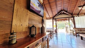 Een houten interieur met een aan de muur bevestigde televisie, een houten bank en een betegelde vloer.