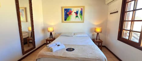A hotel room with a bed, two bedside lamps, a painting on the wall, and a window.