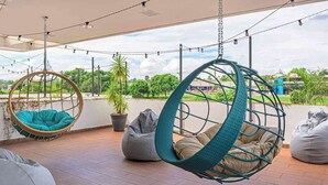 A covered outdoor seating area with hanging chairs and bean bags.