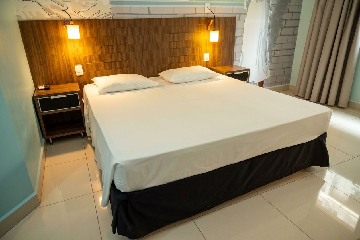 A hotel room with a large bed, two bedside tables, and a wooden headboard.