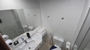 Um banheiro com pia de mármore, um espelho grande, vaso sanitário e chuveiro.