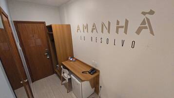 A small room with a desk, chair, and a wardrobe. The wall has the text "AMANHA EL RESOLVO" written on it.