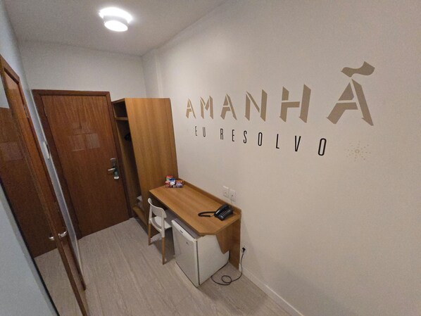 A small room with a desk, chair, and a wardrobe. The wall has the text "AMANHA EL RESOLVO" written on it.