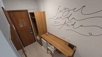 A small room with a wooden desk, a chair, and a wardrobe. There is a wall with a decorative phrase written on it.