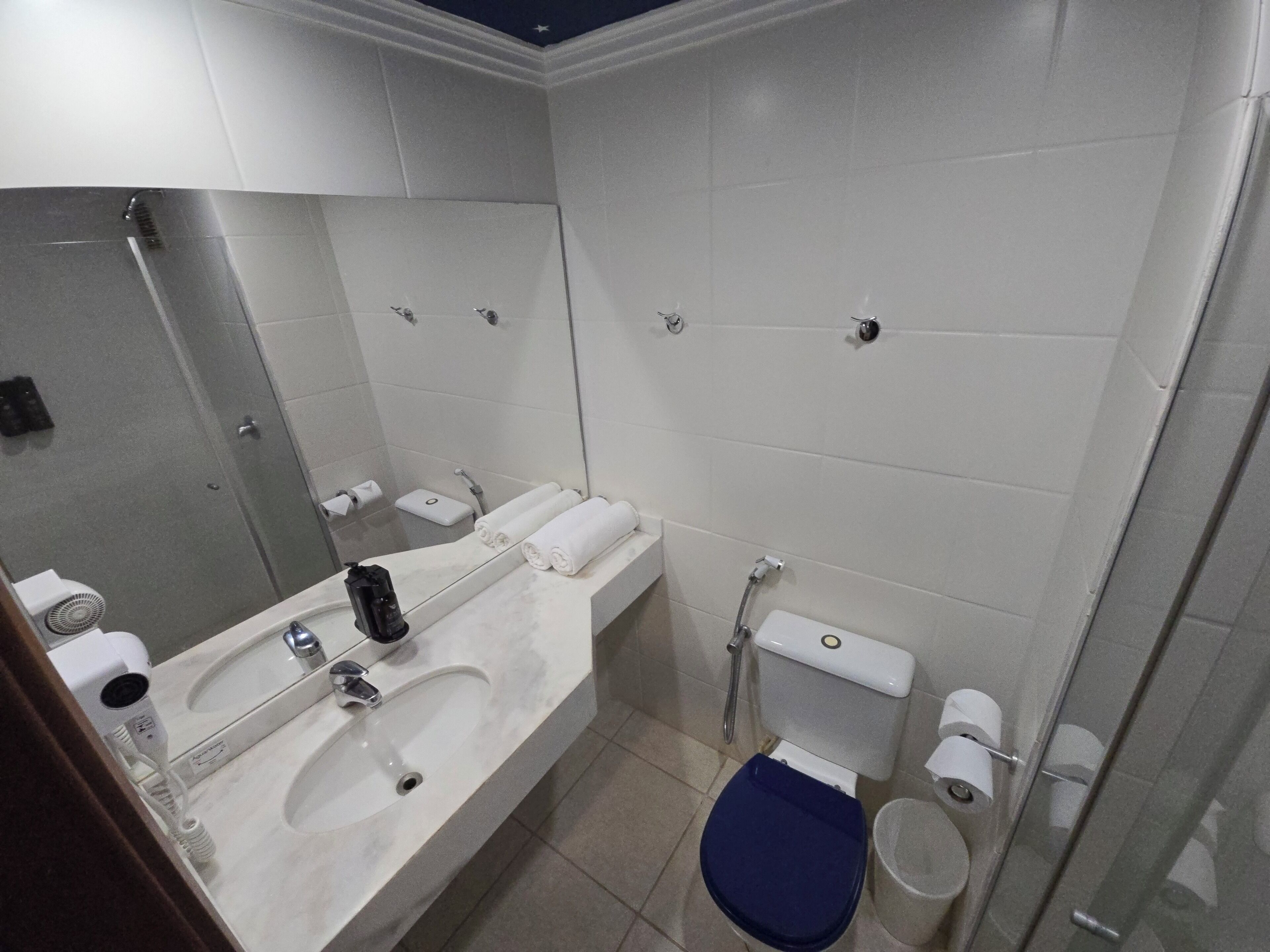 Un baño moderno con un espejo grande, un lavamanos con grifo, un inodoro y un bidé.