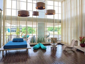 A spacious room with a large window, a bed, a chair, and a small table. - Golden Tower Maurílio Biagi by Fênix Hotéis (Ribeirão Preto)