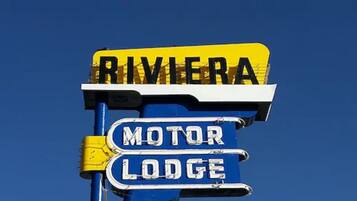 Un letrero con las palabras 'RIVIERA' y 'MOTOR LODGE' contra un cielo azul despejado.