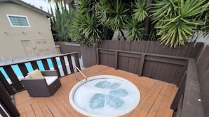 A wooden deck with a hot tub, a wicker sofa, and a wooden fence. - Inn at San Luis Obispo (San Luis Obispo)