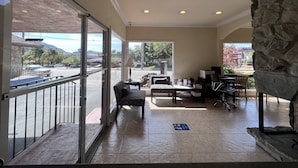 A spacious indoor area with a balcony, a seating area with a table and chairs, and a stone accent wall. - Inn at San Luis Obispo (San Luis Obispo)