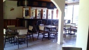Un ristorante con tavoli e sedie, un'area bar con bottiglie e vista all'esterno.