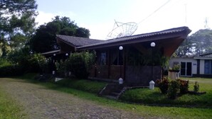Un edificio in stile tradizionale giapponese con tetto spiovente, un’antenna parabolica e un piccolo giardino con dei gradini che conducono all’ingresso.