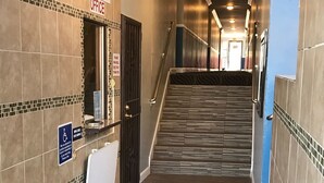 A hotel hallway with a tiled floor, a staircase, and a sign indicating an office. - Relax Inn Motel (Los Angeles)