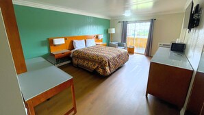 A hotel room with a bed, a desk, a chair, a TV, and a window with curtains. - Relax Inn Motel (Los Angeles)