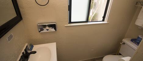 A small bathroom with a sink, toilet, and a window.