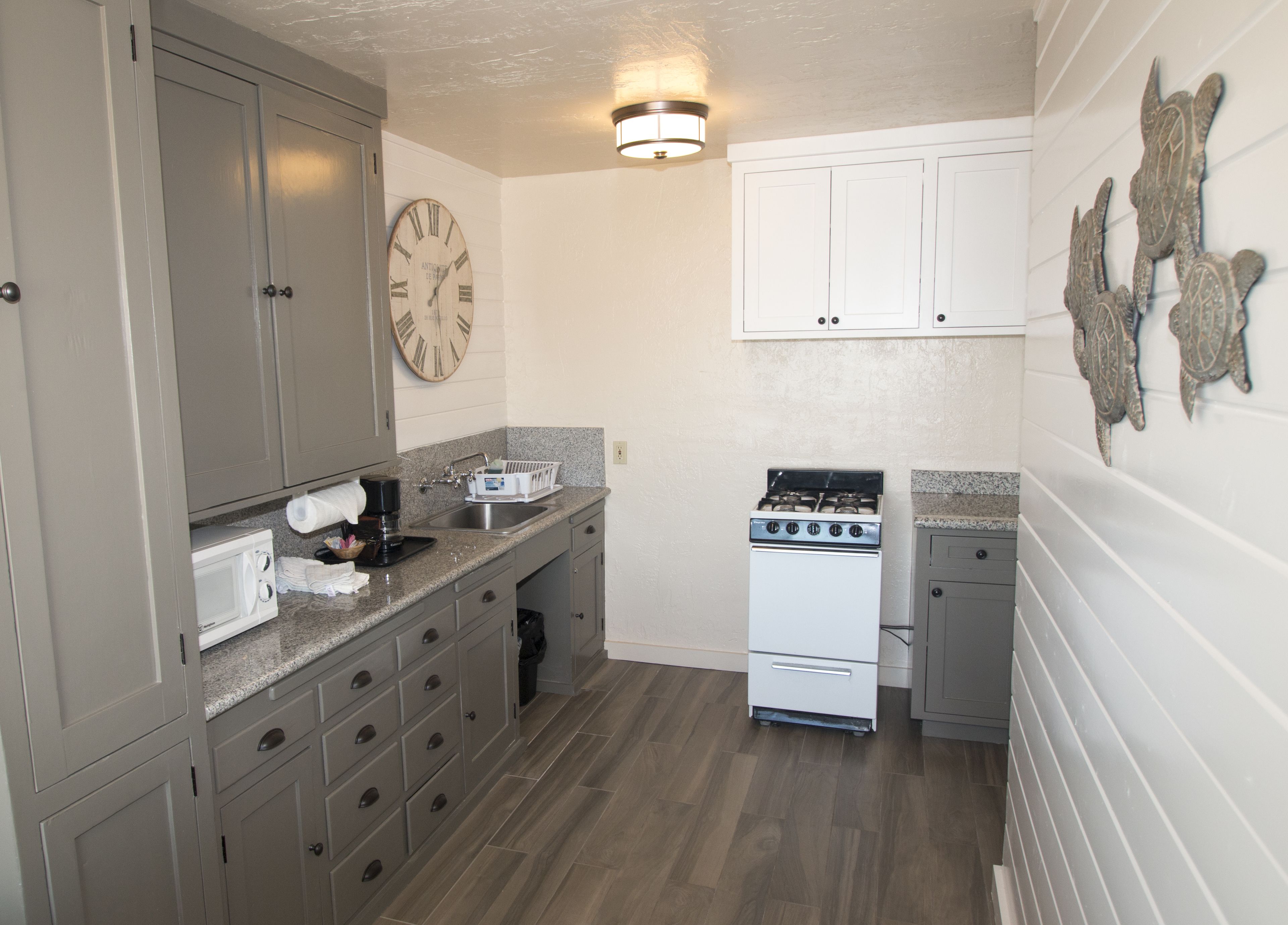 A kitchen with a microwave, sink, stove, and cabinets.