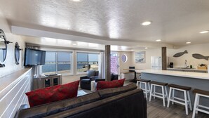 Un intérieur moderne comprenant un espace de vie, une cuisine et de grandes fenêtres donnant sur la mer.