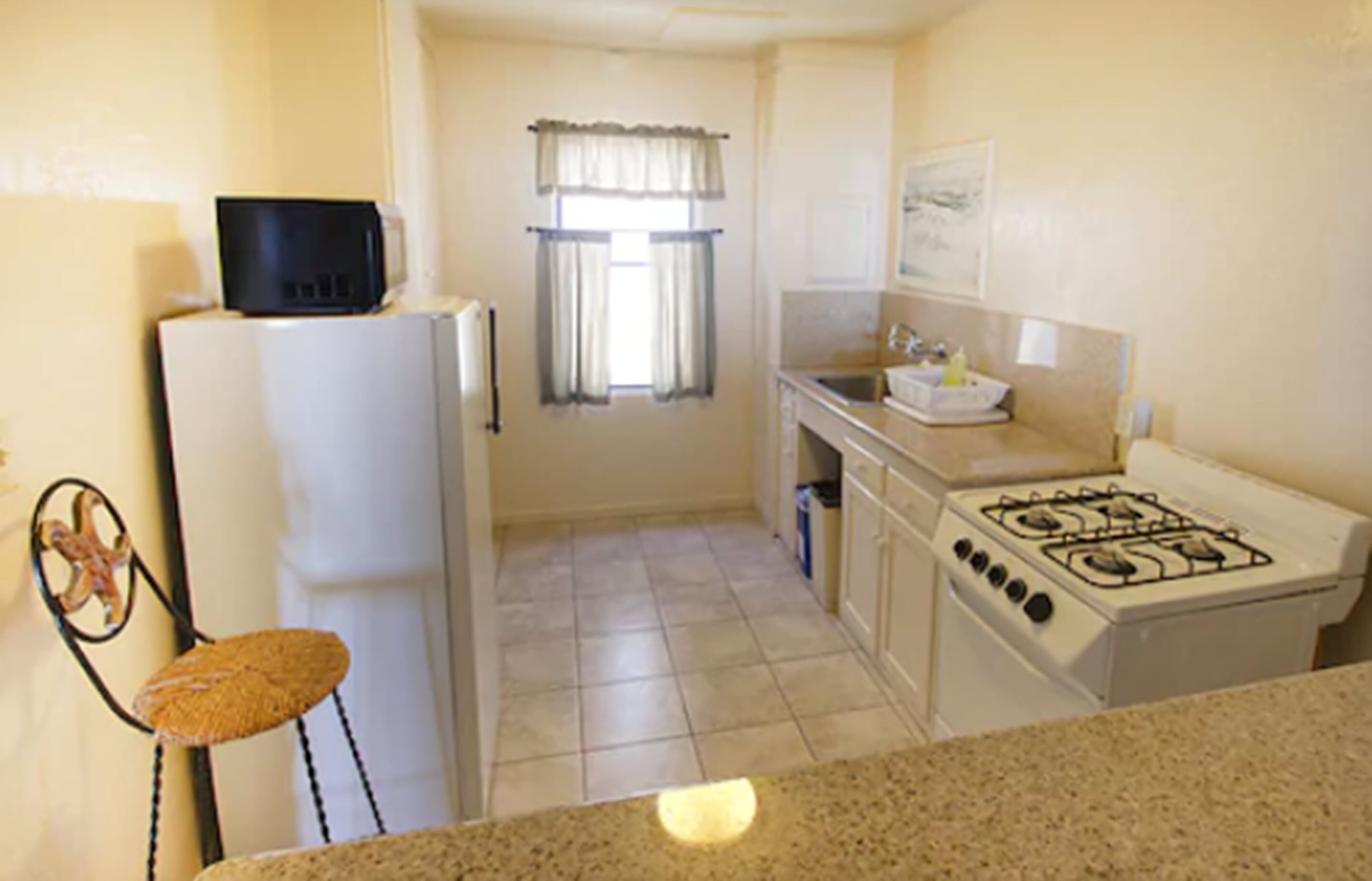 A compact kitchen with a refrigerator, microwave, stove, and a small sink.