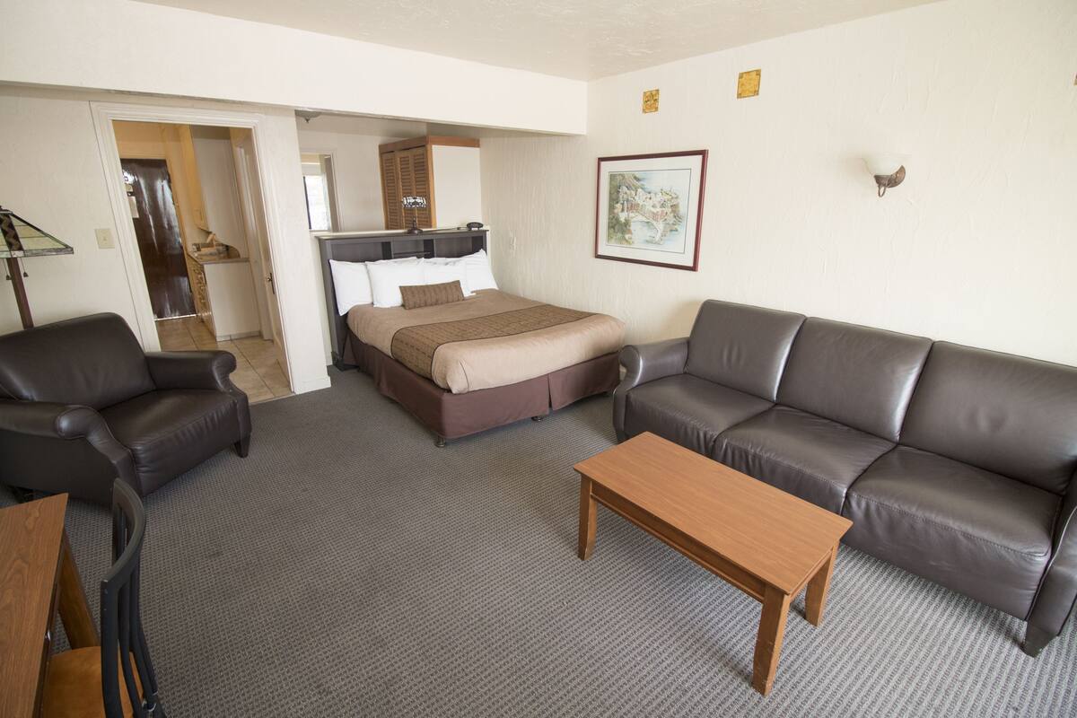 A hotel room with a bed, a sofa, a coffee table, and a desk.
