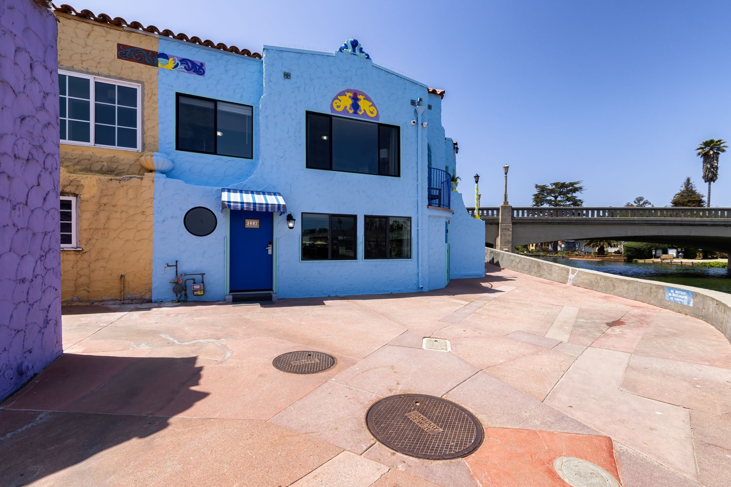 A two-story building with a blue facade, a bicycle symbol, and a blue awning.