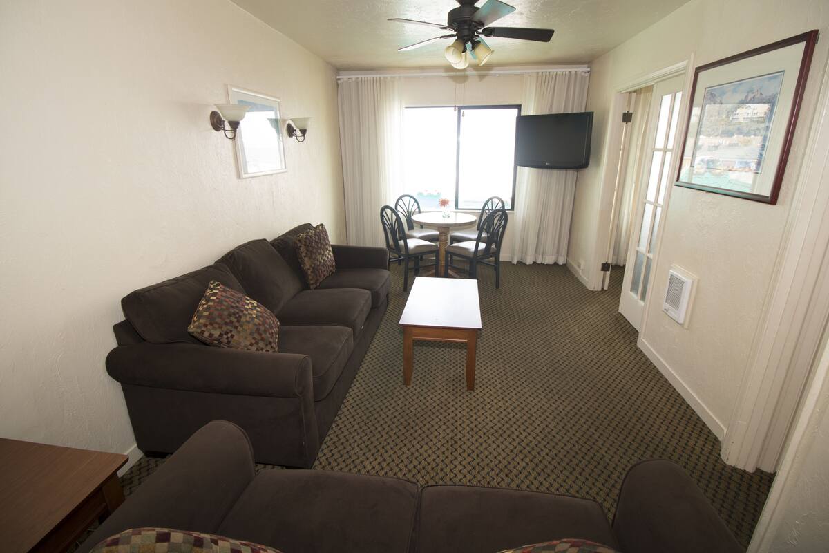 A living room with a sofa, a coffee table, and a TV mounted on the wall.