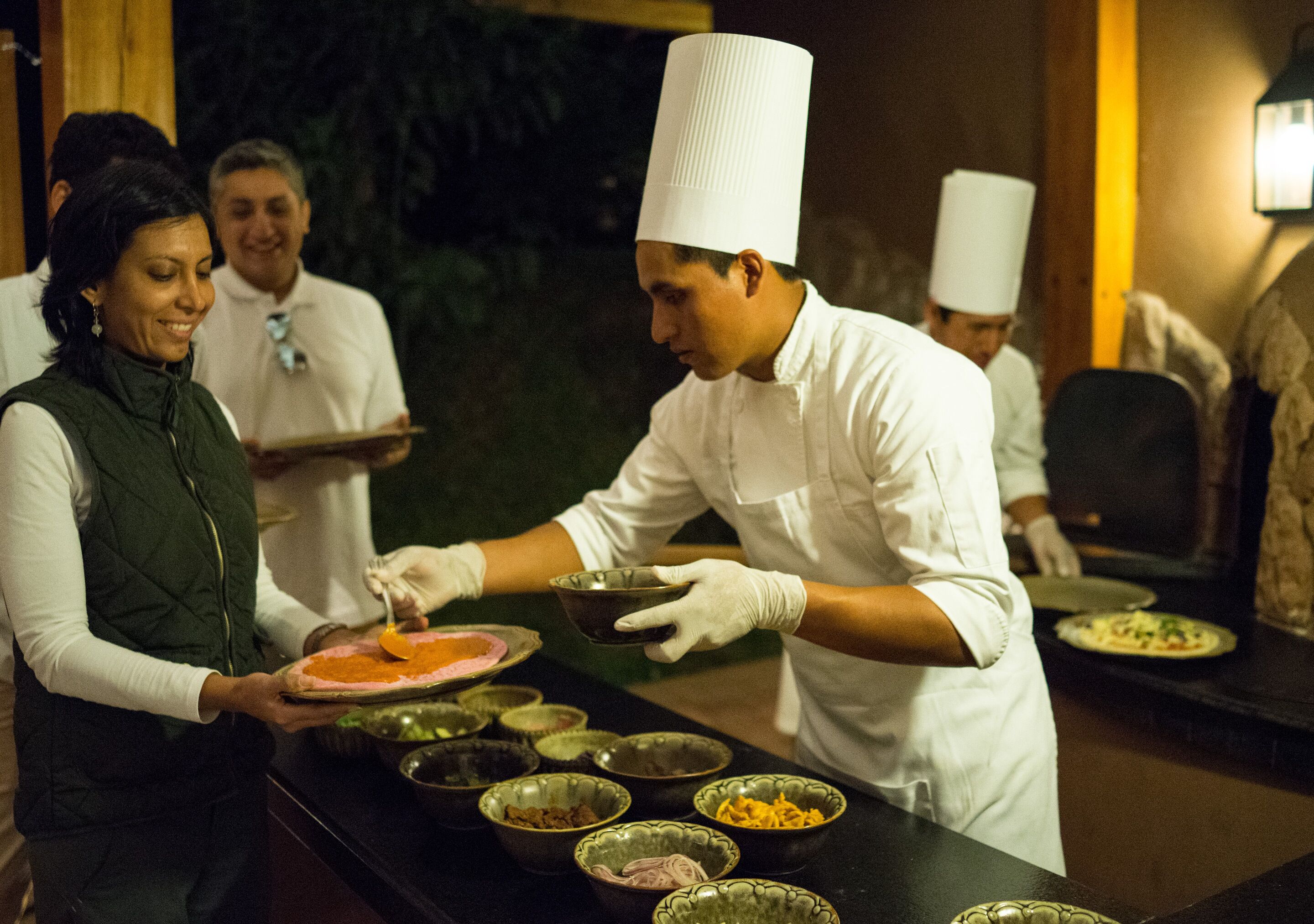 Um cozinheiro a preparar comida numa cozinha profissional, com vários ingredientes e utensílios de cozinha à vista.