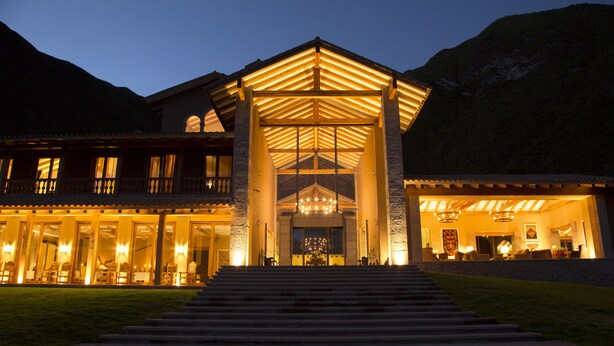 A large, well-lit building with a prominent entrance, multiple windows, and a staircase leading up to the main doors. - Inkaterra Hacienda Urubamba (Huayllabamba)