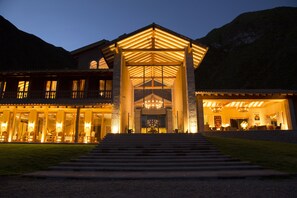 A large, well-lit building with a prominent entrance, multiple windows, and a staircase leading up to the main doors.