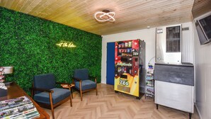 A room with a green wall, two blue chairs, a vending machine, and a small refrigerator. - The Lake House Inn (Laurie)