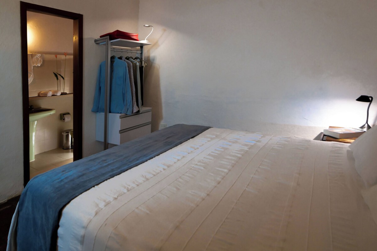 Une chambre d’hôtel comprenant un lit, une table de chevet, un bureau, un miroir et une armoire.