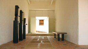 A hallway with a stone floor, a bench, and a door leading to a bright room. - La Nube Posada (Barichara)