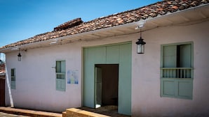A traditional building with a tiled roof, light-colored walls, and green shutters. - La Nube Posada (Barichara)