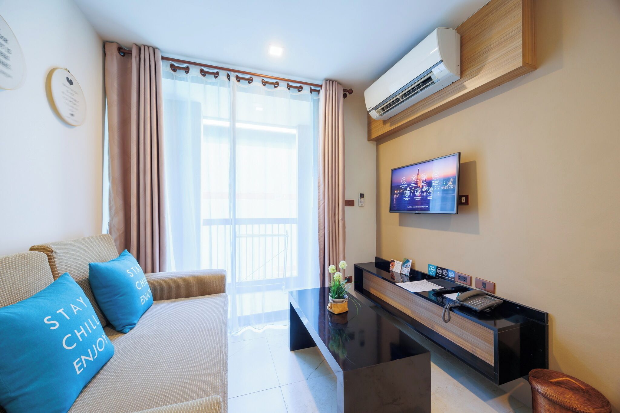 Ein Hotelzimmer mit einer Couch, einem Couchtisch, einem Fernseher und einer Klimaanlage.