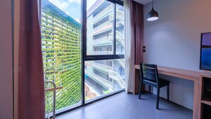 A modern room with a large window, a desk, a chair, and a TV. - Cross Vibe Chiang Mai Decem (Chiang Mai)