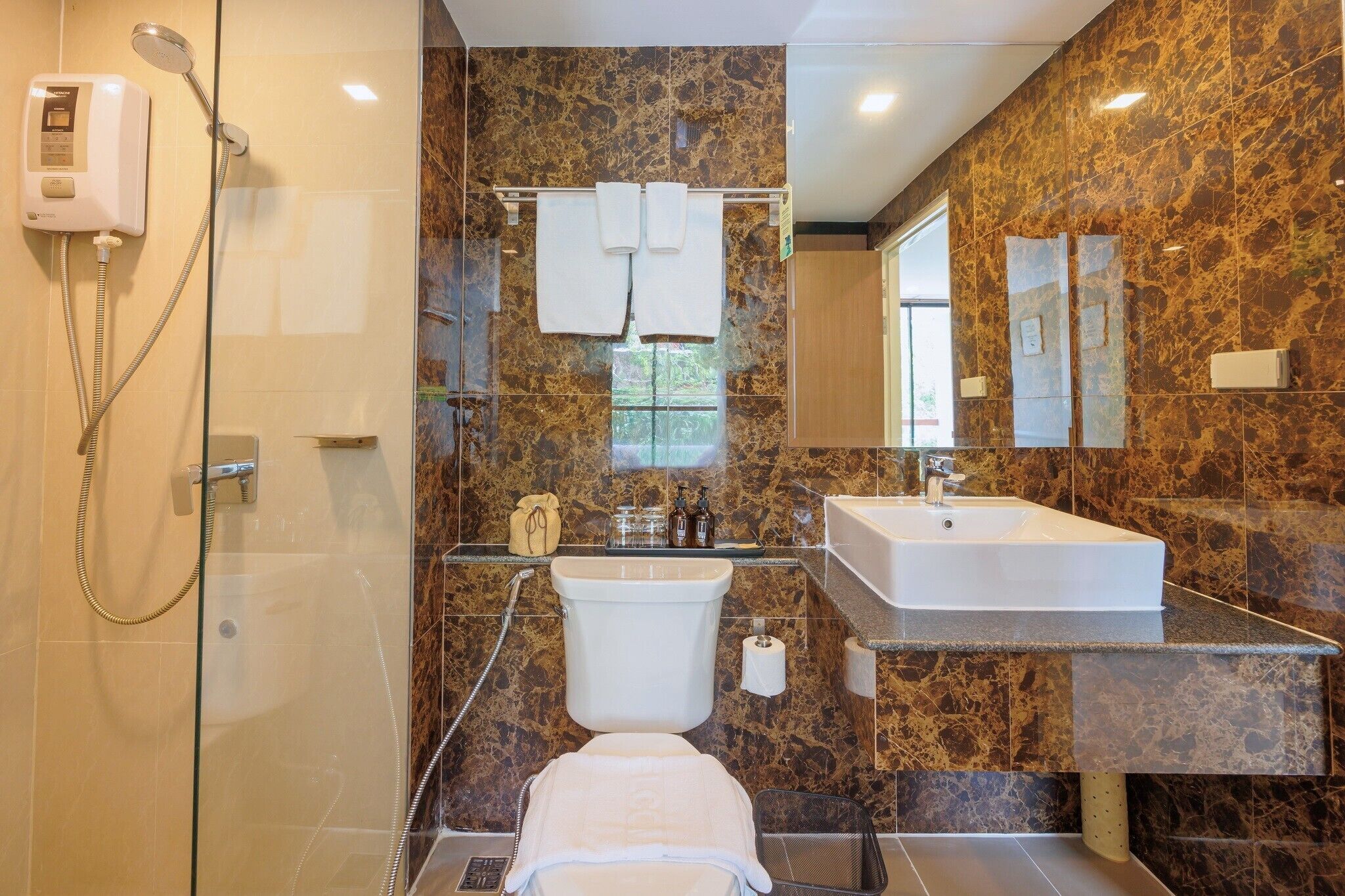 Un baño con ducha de vidrio, inodoro, lavamanos y espejo.