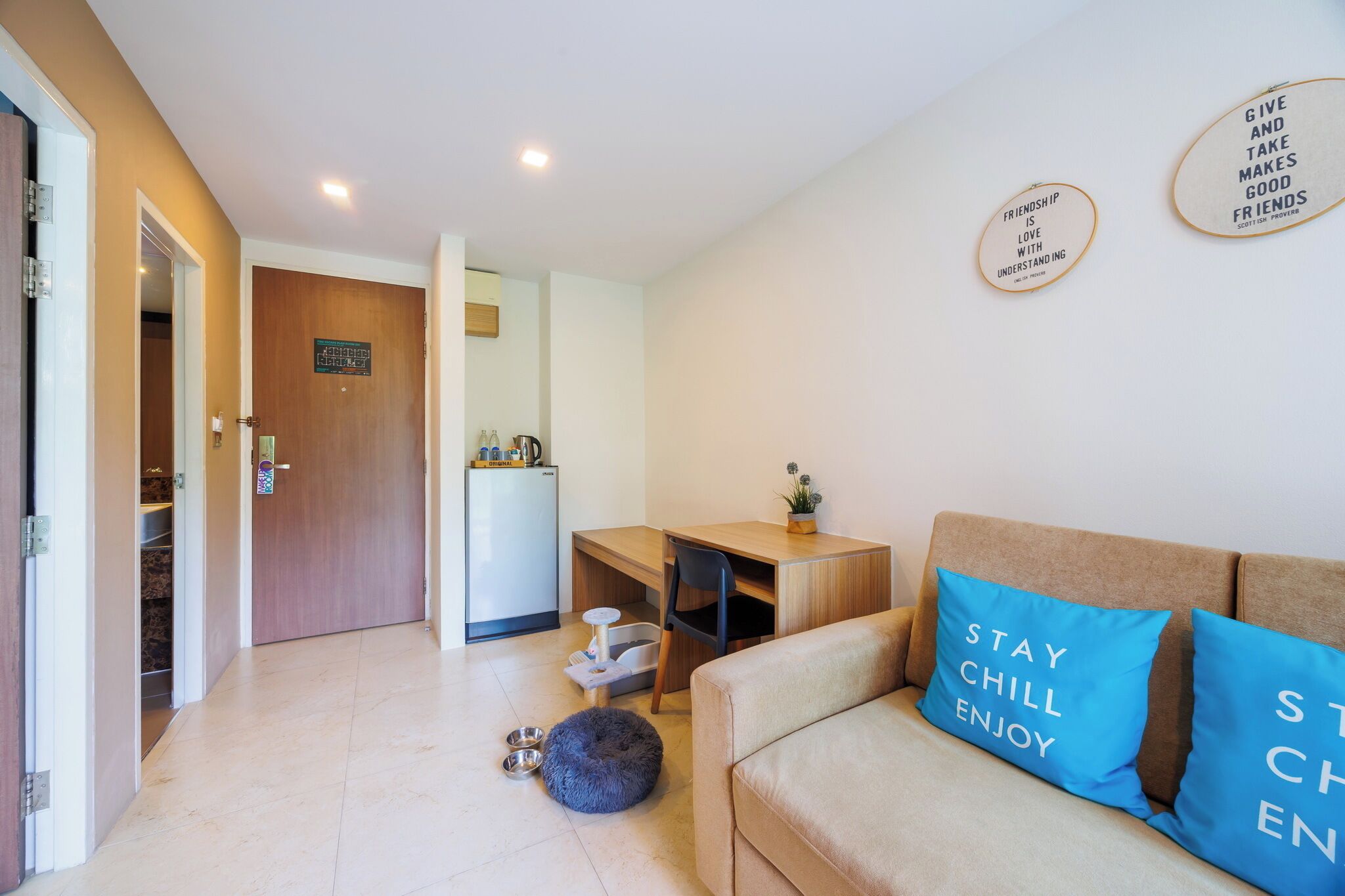 A living room with a sofa, a table, and a small kitchen area in the background.