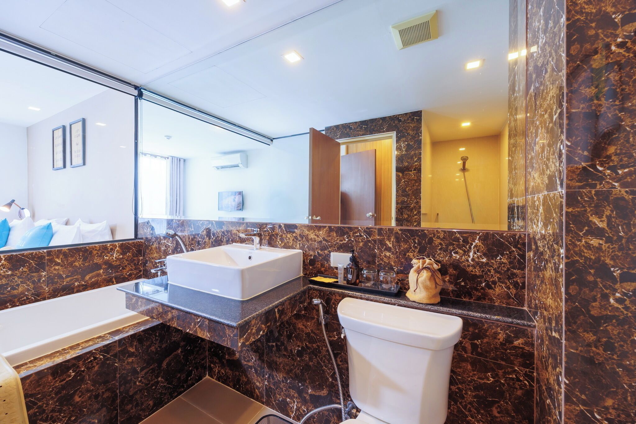 Un baño moderno con un espejo grande, dos lavamanos, un inodoro y una ducha.