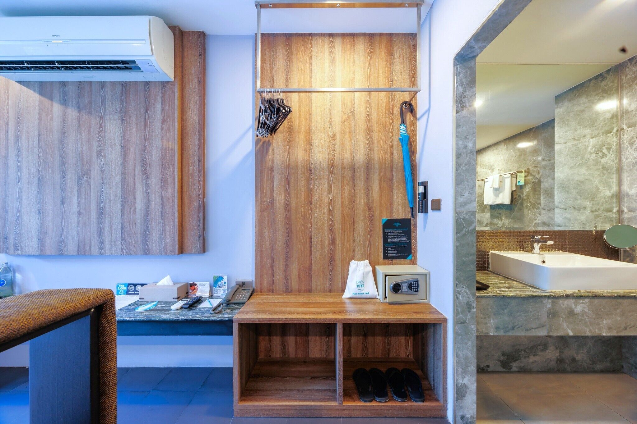 A bathroom with a wooden vanity, a shower, a sink with a marble countertop, and a towel rack.