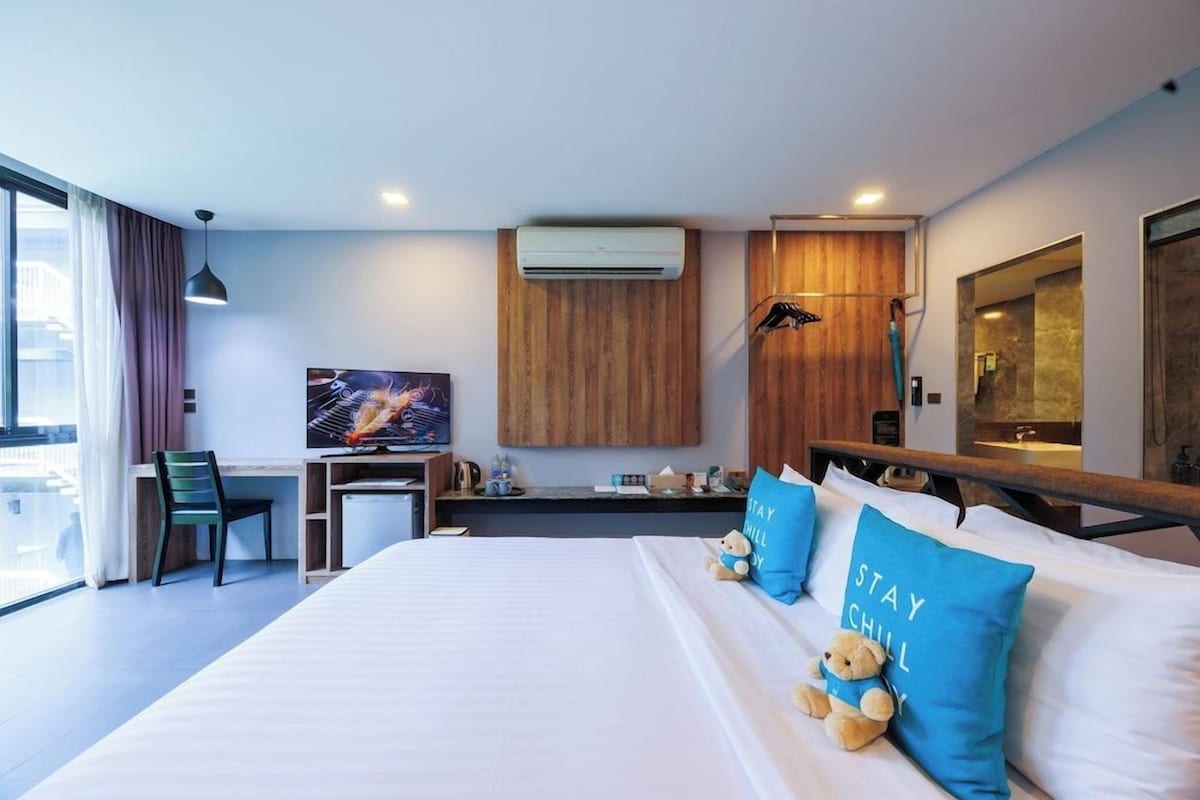 Una habitación de hotel moderna con una cama grande, un escritorio y un televisor.